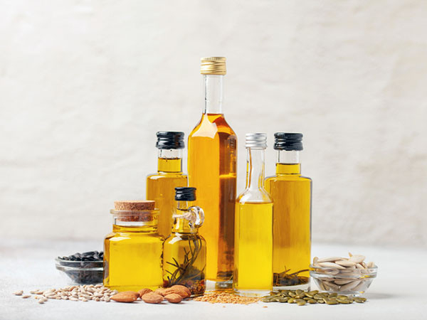 photo of an assortment of different types of plant-based oils in bottles against a light background